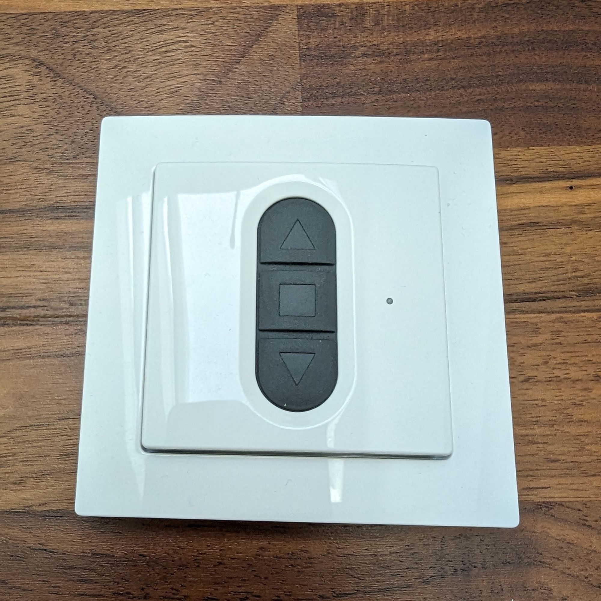 A white wall switch for window covers with 3 buttons. 