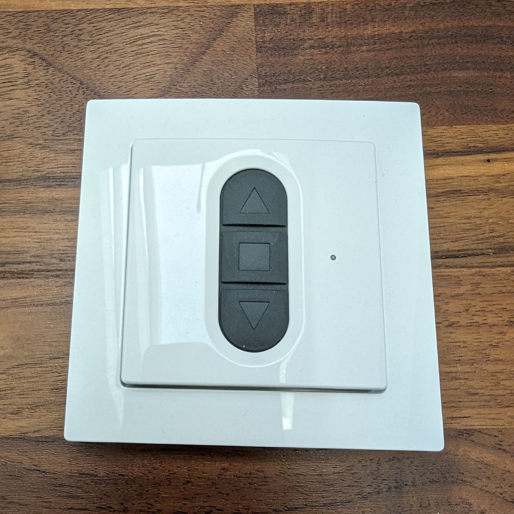 A white wall switch for window covers with 3 buttons.