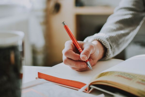 Person writing into a book with a pen